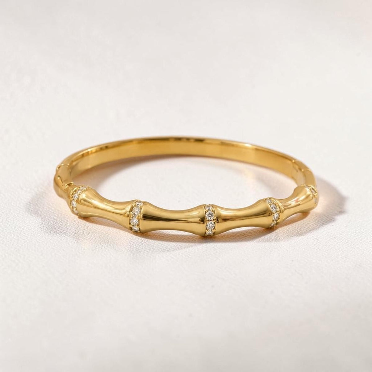 Altin Noor gold bamboo-inspired stackable ring with shimmering cubic zirconia accents on a textured white background.