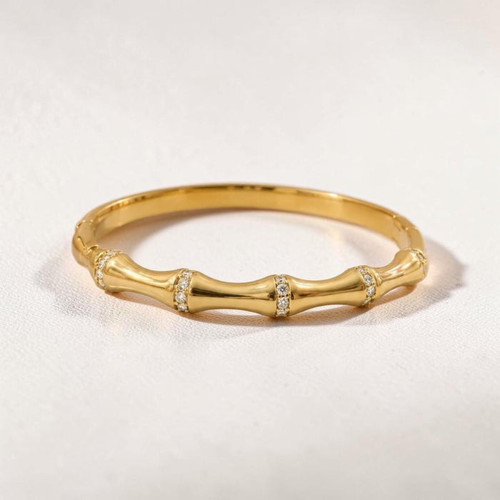 Altin Noor gold bamboo-inspired stackable ring with shimmering cubic zirconia accents on a textured white background.