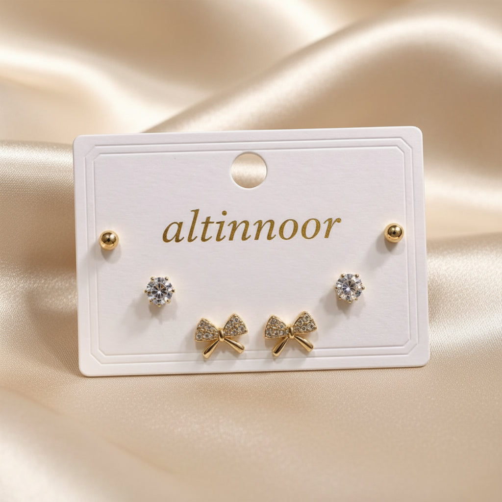 Altin Noor earring set featuring gold-tone ball studs, solitaire cubic zirconia, and crystal-encrusted bow studs.
