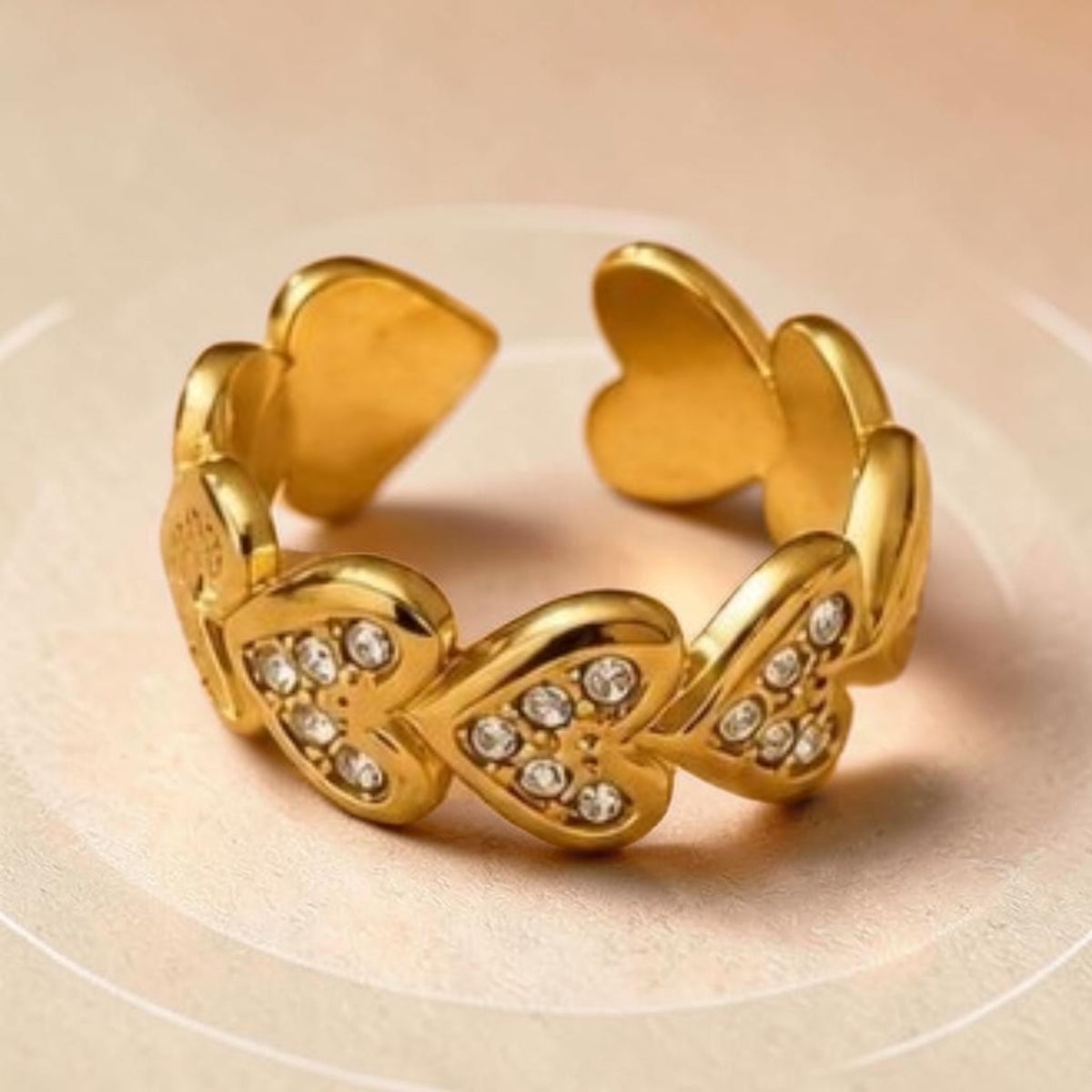 Altin Noor gold-tone open band ring featuring interconnected heart motifs encrusted with shimmering clear crystals.