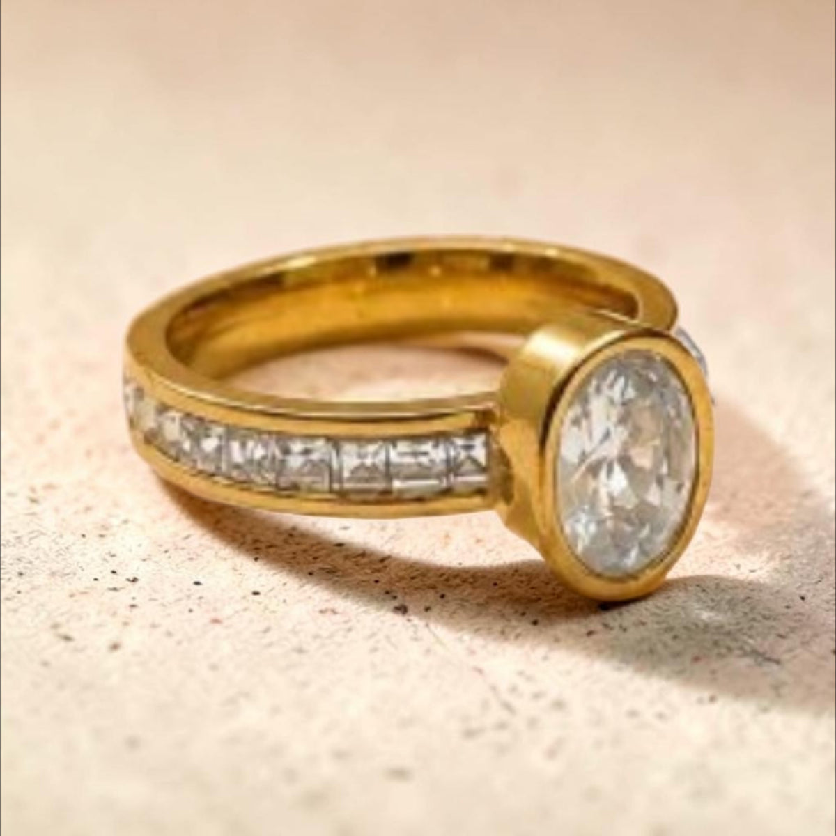 Altin Noor gold-tone statement ring featuring a central oval-cut stone and channel-set square crystals on the band.