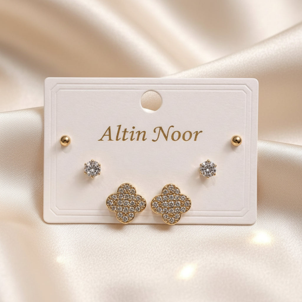 Altin Noor three-piece gold-tone earring set featuring ball studs, solitaire crystals, and pavé clover motifs.