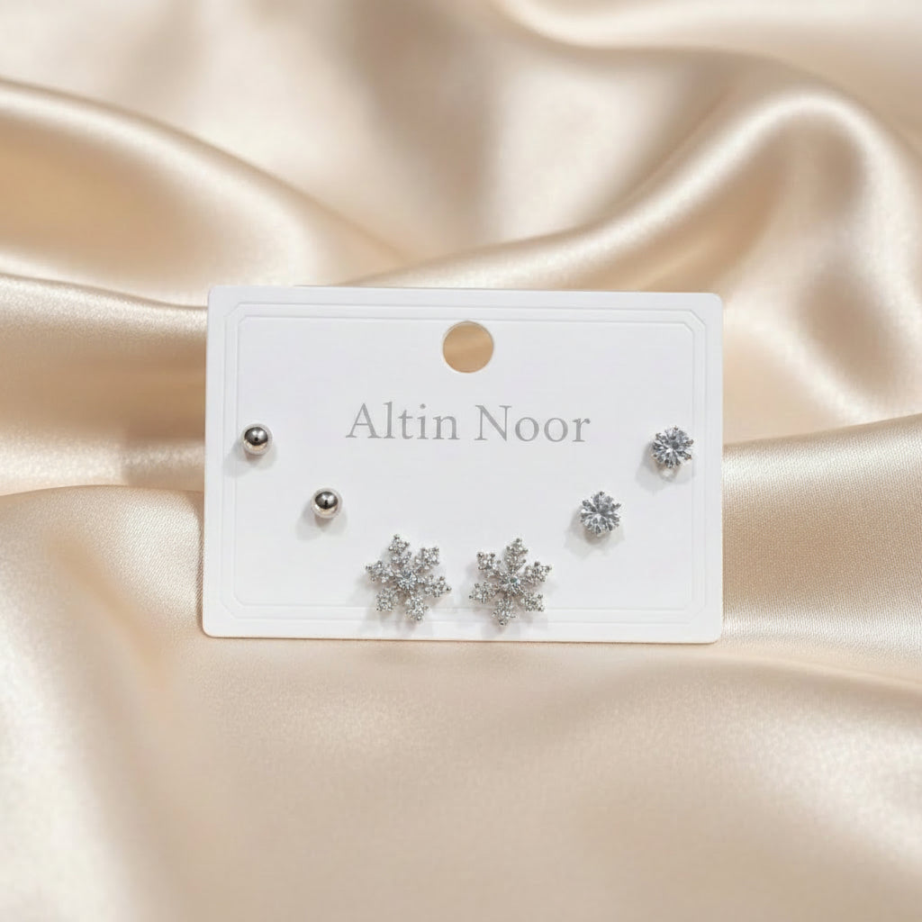 Altin Noor three-pair earring set featuring silver ball studs, cubic zirconia solitaires, and crystal snowflake studs.