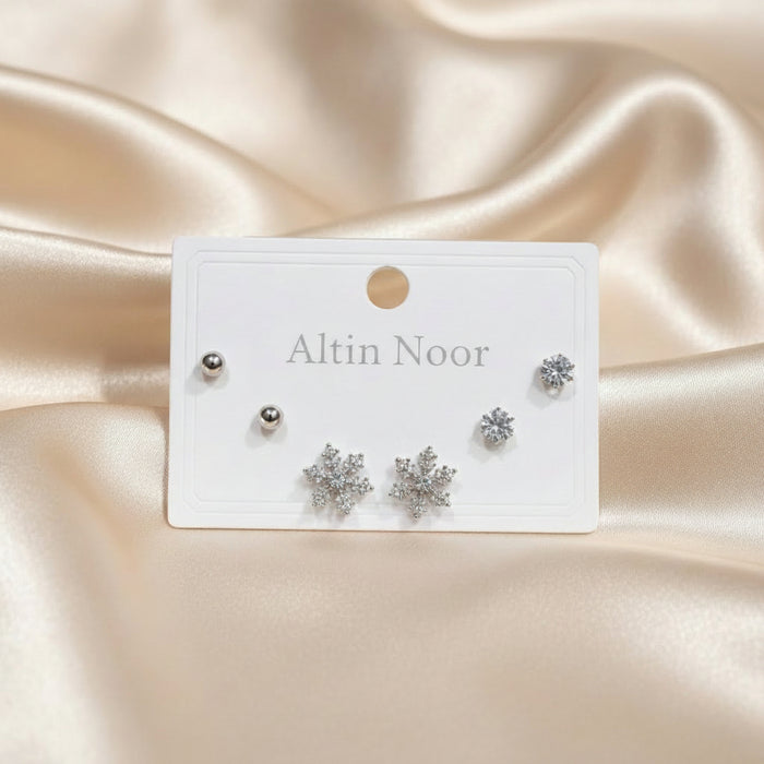 Altin Noor three-pair earring set featuring silver ball studs, cubic zirconia solitaires, and crystal snowflake studs.